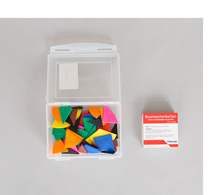 Eine durchsichtige Plaste-Box mit Verschluss, die Kunststoff-Legematerial enthält, das die Bruche von 1/1 bis 1/12 darstellt. Daneben liegen Bruchrechenkarten mit Aufgabenstellungen.