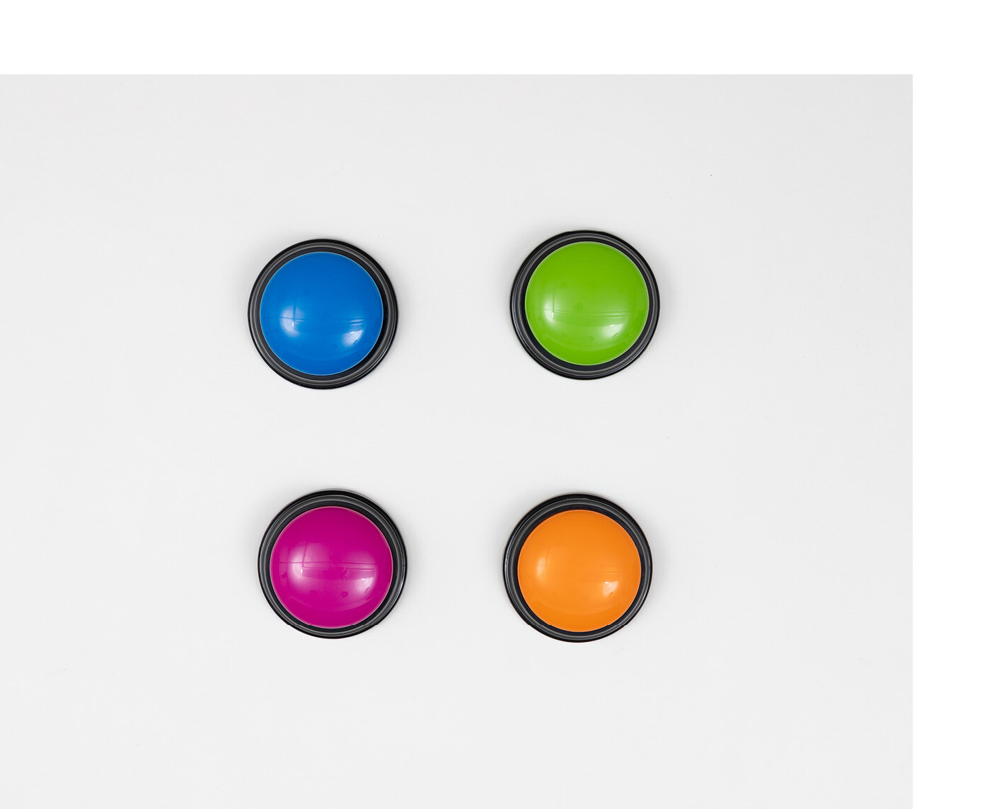 Vier unterschiedlich farbige Buzzer liegen zu einem Viereck angeordnet