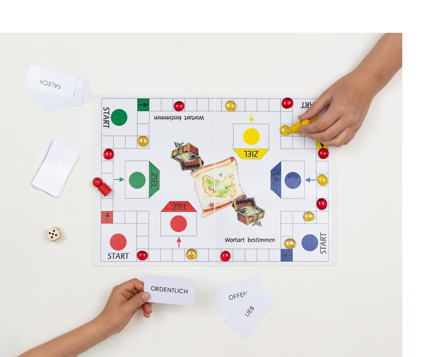 Spielfiguren stehen auf dem Spielfeld und daneben Karten mit Wörtern darauf.