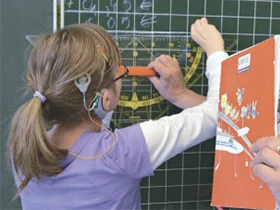 Mädchen mit Hörgerat an einer Schultafel